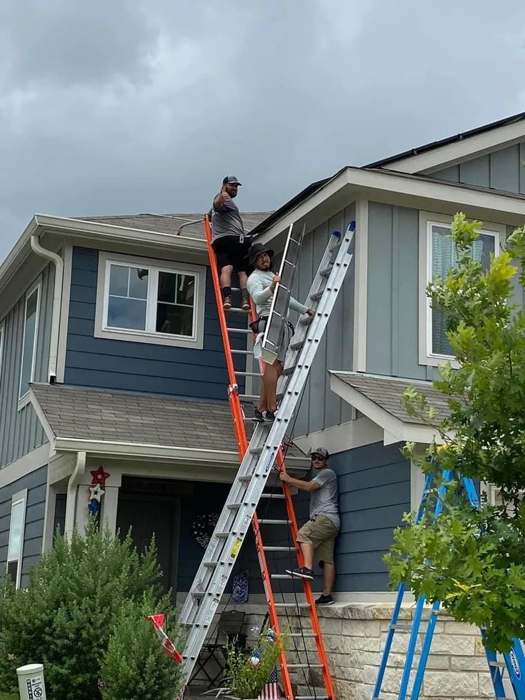 Technician repairing a home's gutter system from a ladder